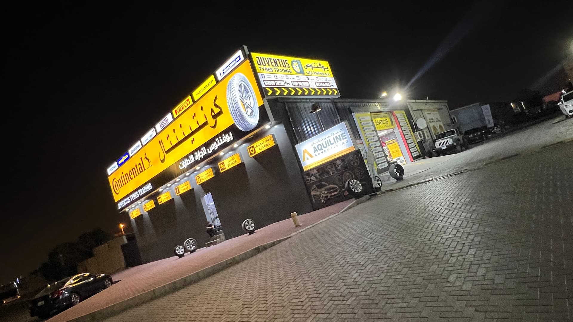 The Juventus Tyres Trading unit on 4th Street at night, signage lit