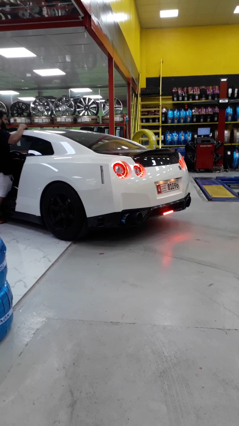 A Nissan GT-R in the workshop beside the alloy wheel display