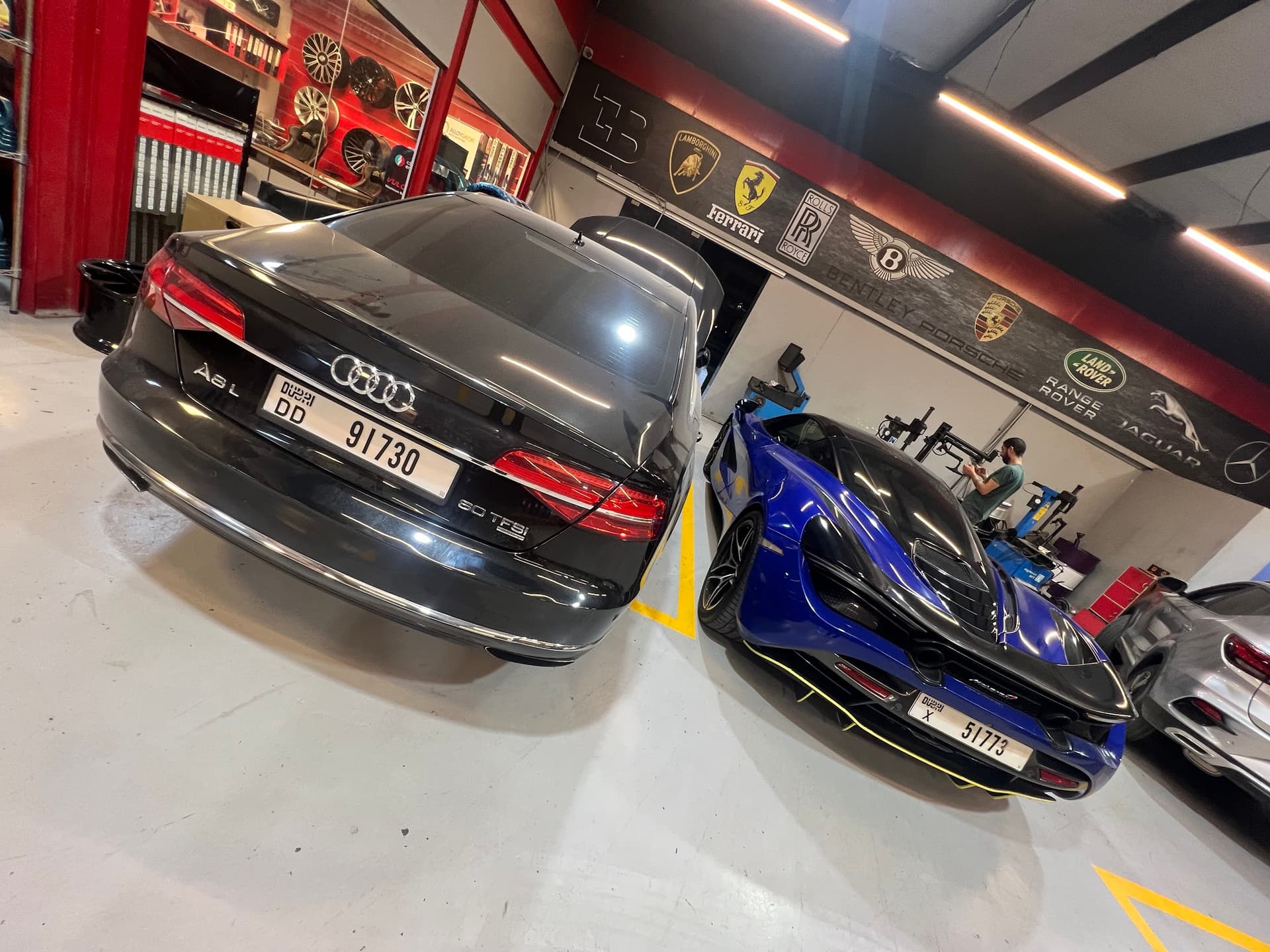 An Audi and a McLaren in the Juventus workshop, below a wall of manufacturer badges